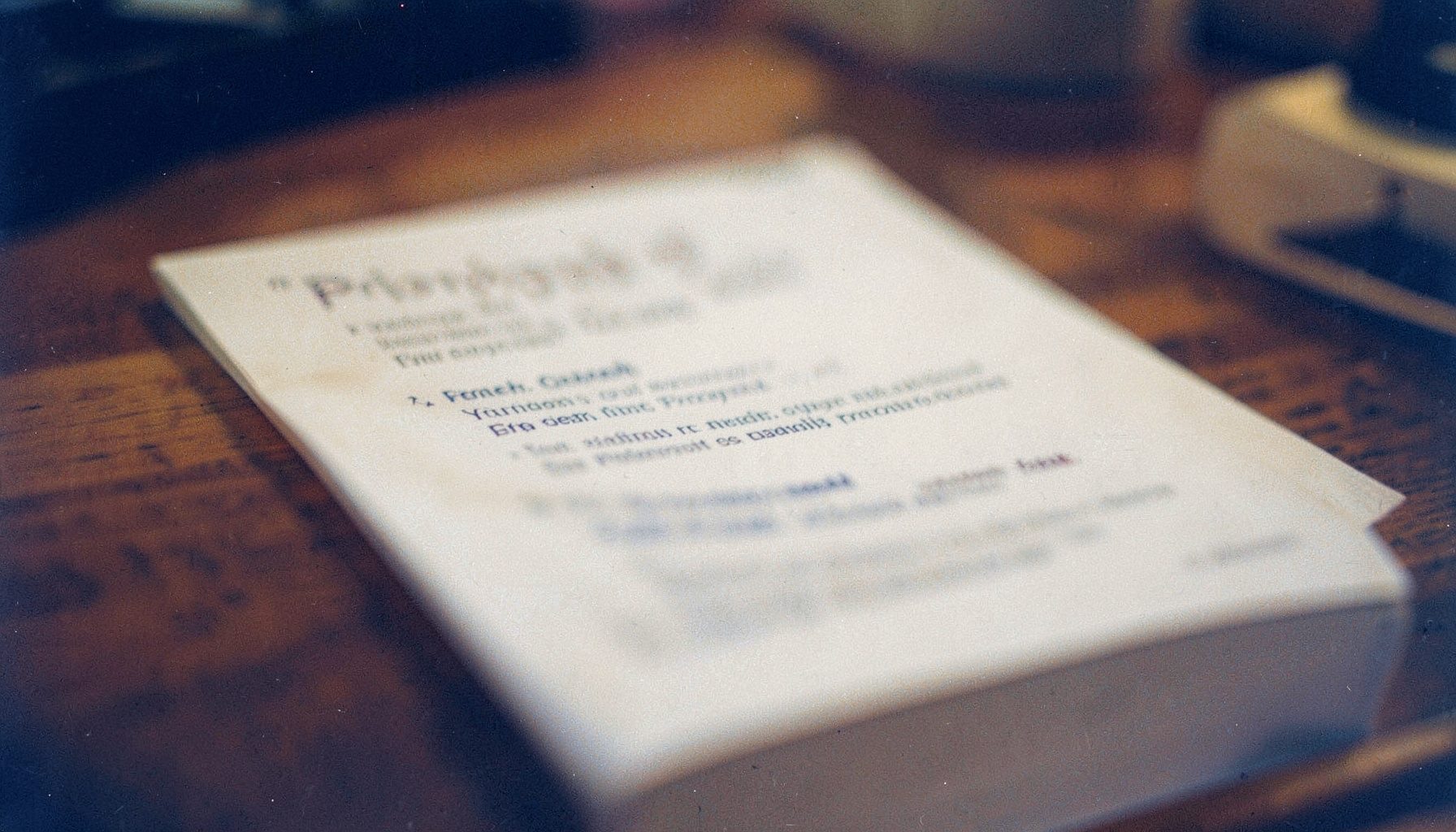A softly blurred close-up of a privacy policy document on a wooden desk, warm amber and navy tones, shallow depth of field, visible film grain